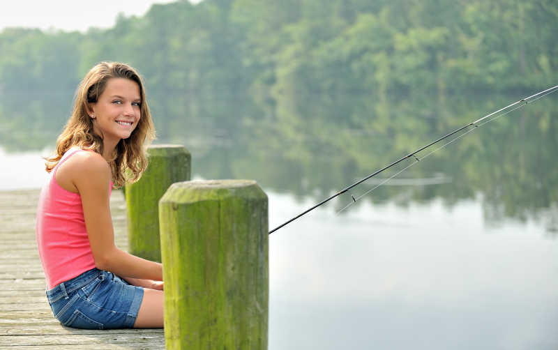 坐在码头上钓鱼的年轻人