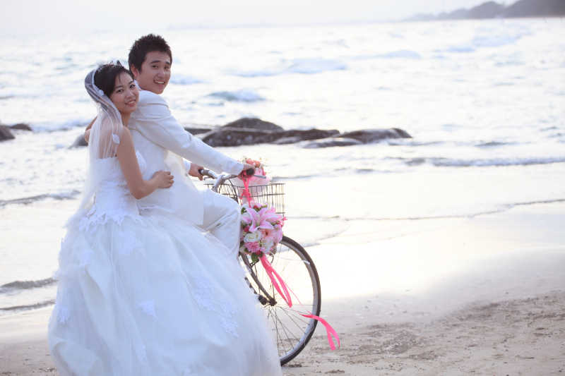 沙滩上骑自行车的新婚夫妇