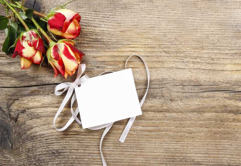 木制背景下的黄红色玫瑰花和卡片