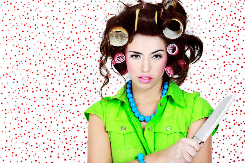 白底红点背景下穿绿色衣服卷着头发的家庭主妇拿着水果刀