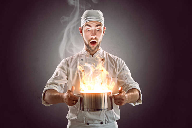 厨师惊讶的端着一个冒火的锅