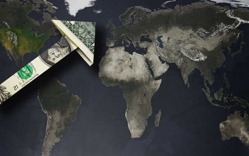 放在地球图案上折成箭头的美金