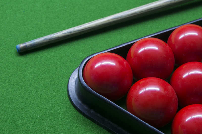 绿色台球桌上的红色台球和台球杆