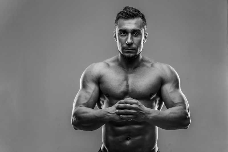 双手抱拳的肌肉男黑白