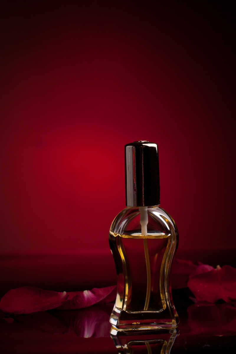 红色的玫瑰花瓣在香水瓶下