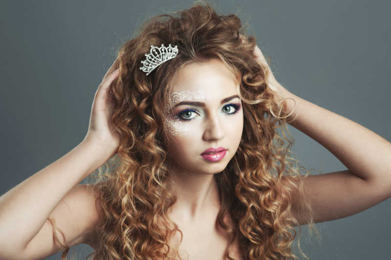 头戴皇冠画着精致妆容的金色卷发小女孩