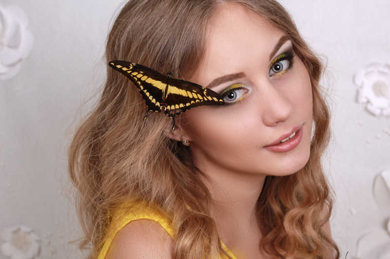 一头金色秀发的美女头上停落者一只蝴蝶