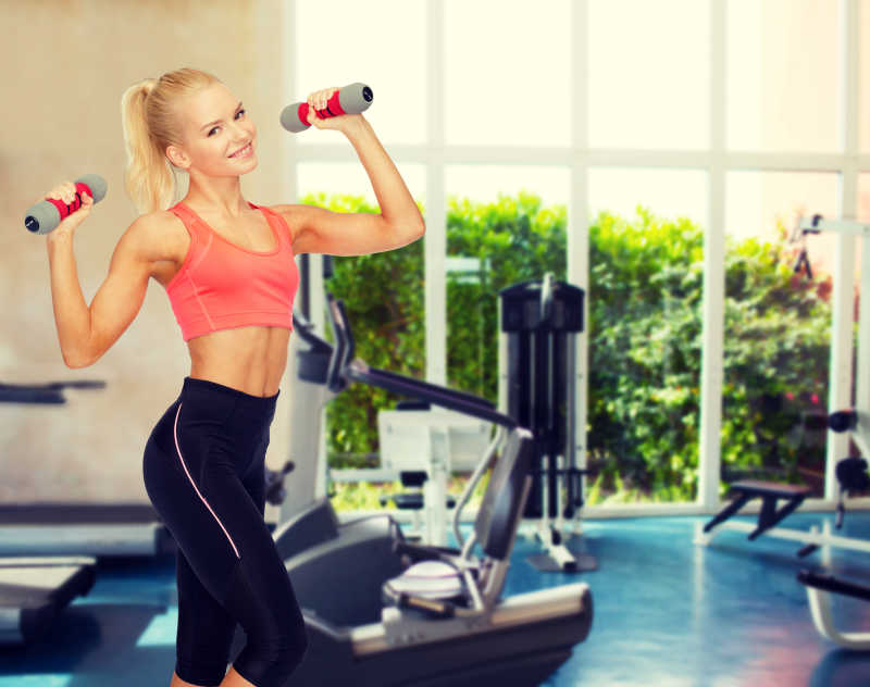 健身房里双手举着哑铃的健身美女