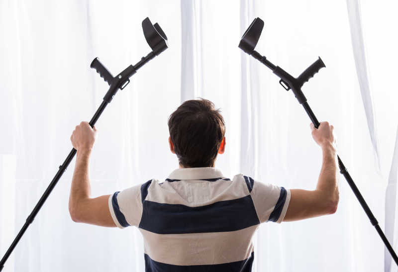 年轻人的背影手拿着拐杖