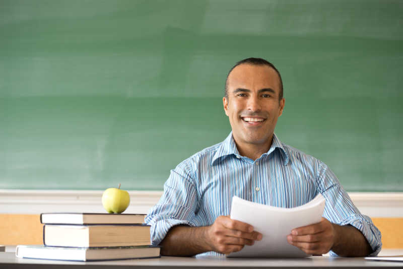 微笑的男老师坐在黑板前