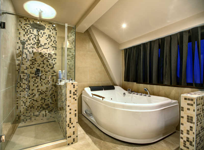 简约马赛克装修浴室里的浴缸和玻璃围挡冲凉房