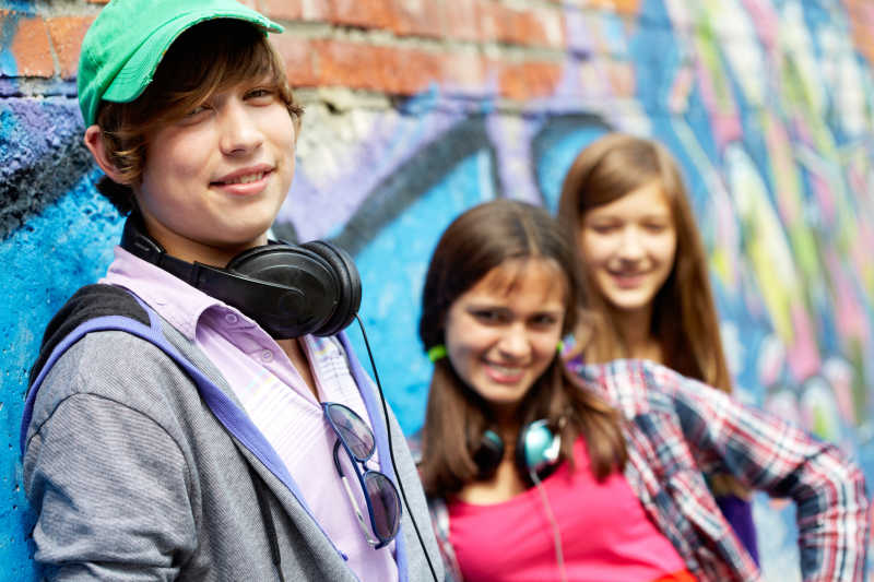 站在涂鸦墙前的微笑的少男少女