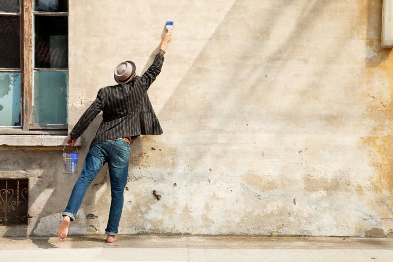 一个人拿着刷子在黄色的墙上画