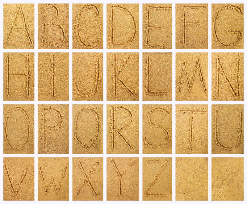 沙子背景上的手写字母
