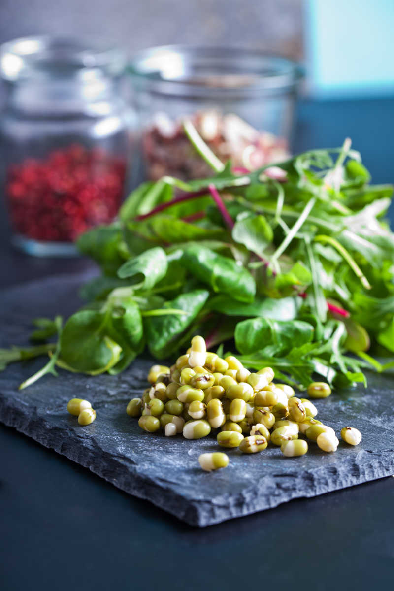 黑色背景下的绿豆和香草