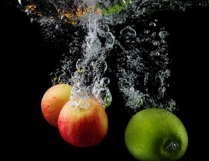 黑色背景下的水里有气泡的苹果抓拍