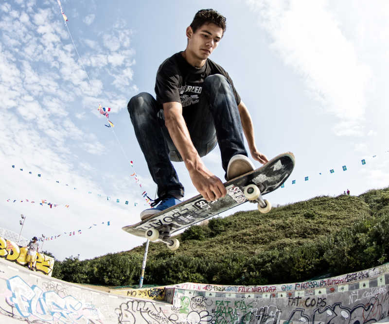 参加滑板比赛玩滑板跳跃的年轻男子