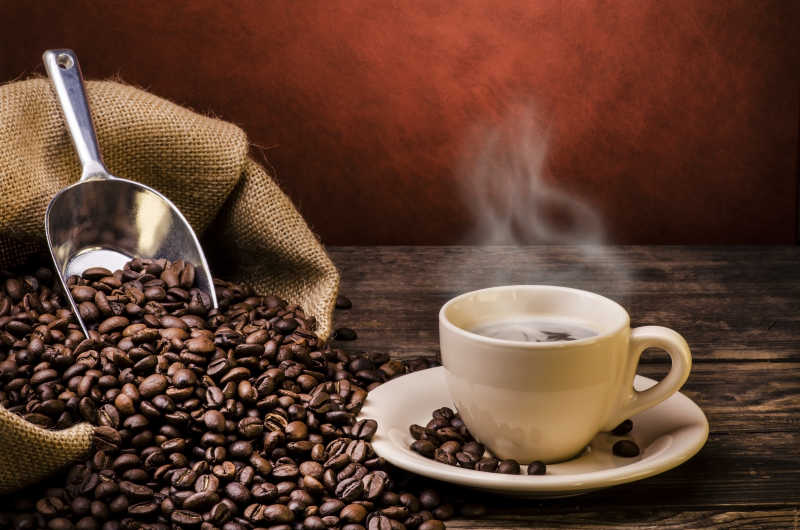 棕色木桌上的热咖啡和咖啡豆