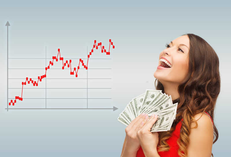 灰色背景下微笑的女人用美元做交易