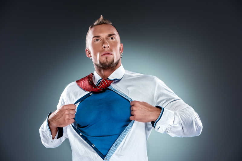 灰色背景下撕掉自己衬衫的男人想象自己像个超级英雄