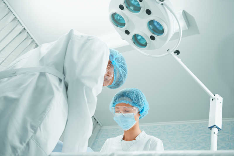在手术灯下进行手术的两个外科医生