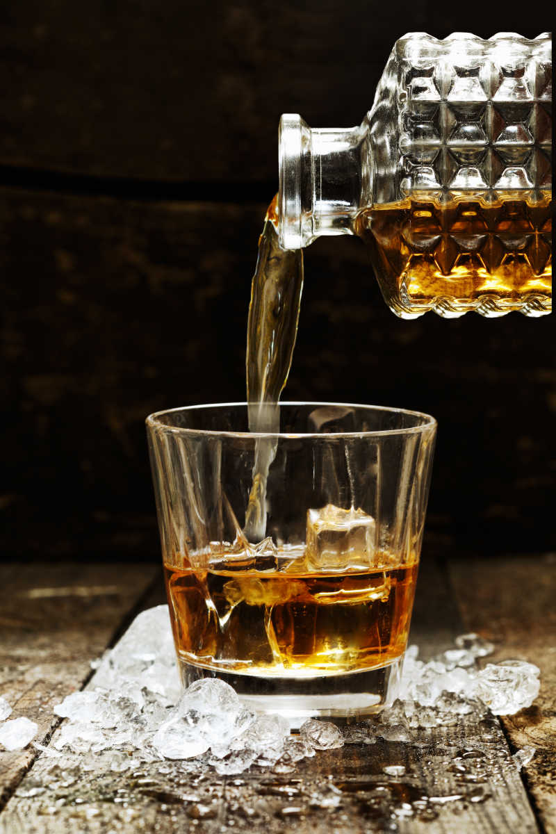 浇威士忌或苏格兰从水瓶变成冰块的杯子里