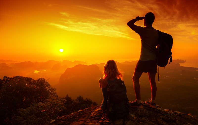 站在山顶上欣赏山谷日出的徒步旅行者