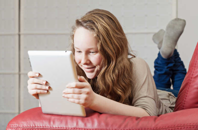趴在沙发上玩平板电脑的女孩