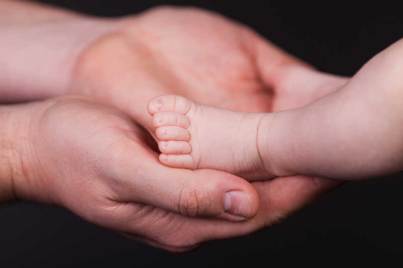 大人双手捧着婴儿的脚