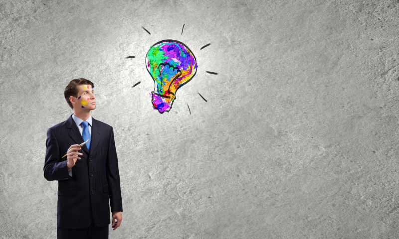 在墙上画彩色灯泡的商人