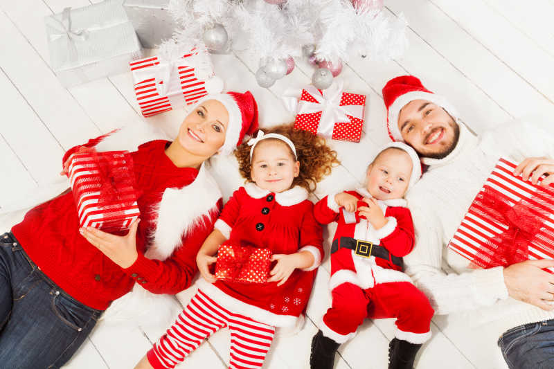 穿着圣诞装躺在白色地板上的幸福家庭