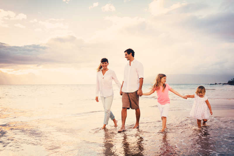 在海边牵手散步的幸福家庭