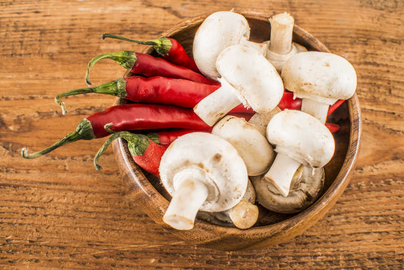 木质碗里的白蘑菇和红辣椒