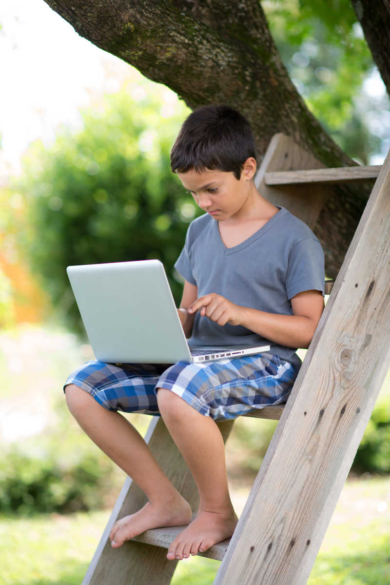 户外使用笔记本电脑的小男孩
