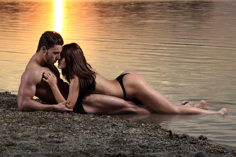 年轻性感的夫妇在海滩上空的日落低光