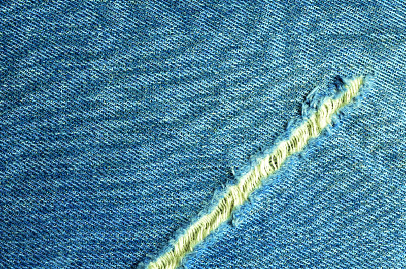 蓝色牛仔裤纹理和划开的口子