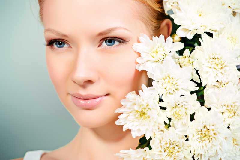 美丽的金发女孩与白色菊花