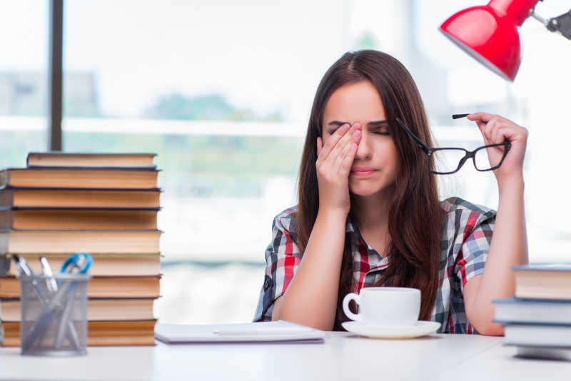 准备大学考试的年轻女学生眼睛非常疲劳