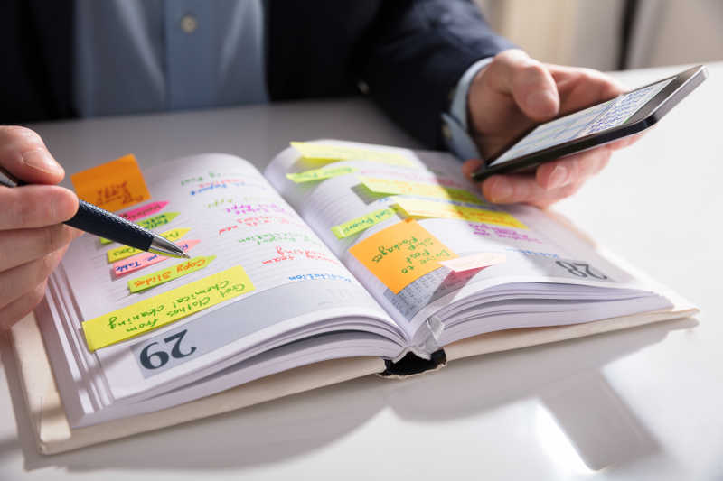 看着手机做笔记的商人