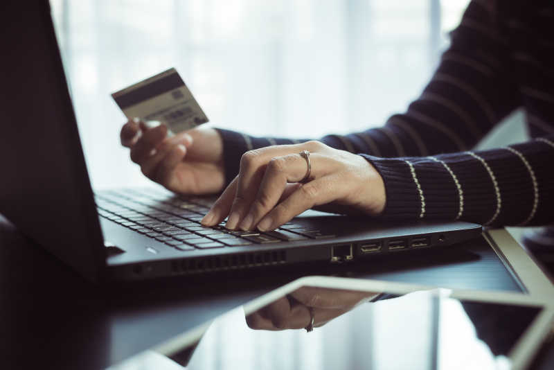 手持信用卡的女性用笔记本电脑进行网上购物