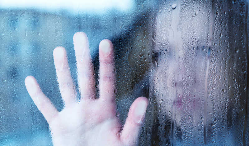 年轻女子的受在雨中的窗口