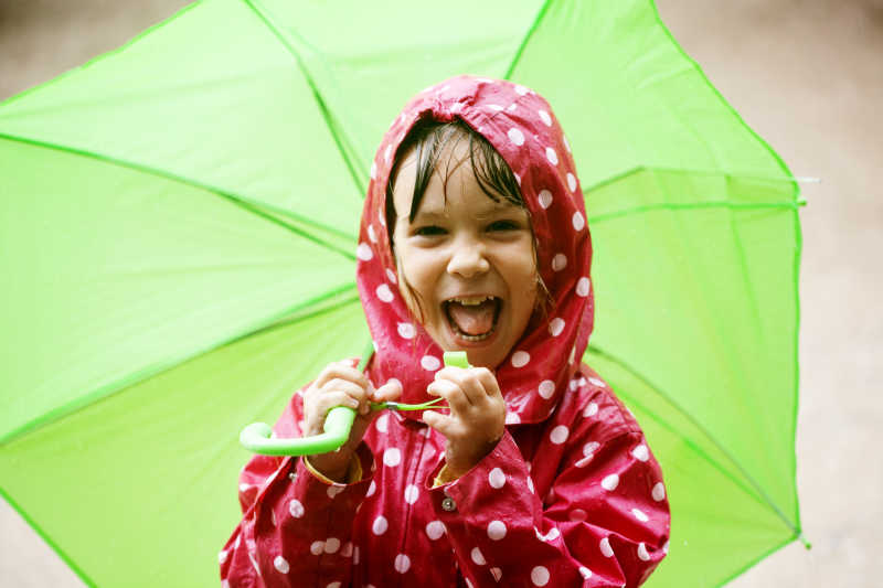 雨中打着绿色伞的小女孩