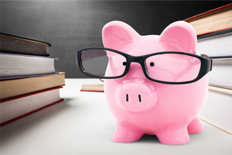 图书背景下的粉色小猪存钱罐