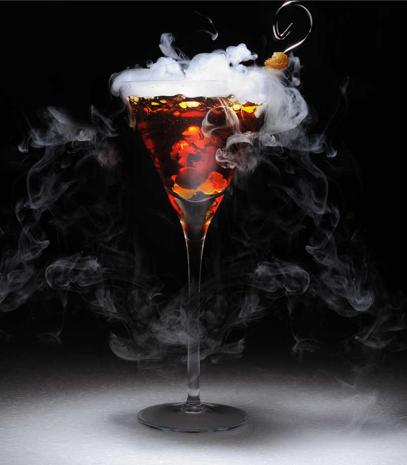 黑色背景上的冒着白烟的鸡尾酒
