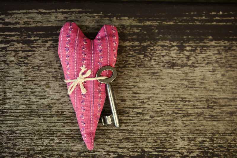 木桌上的粉色心形与钥匙