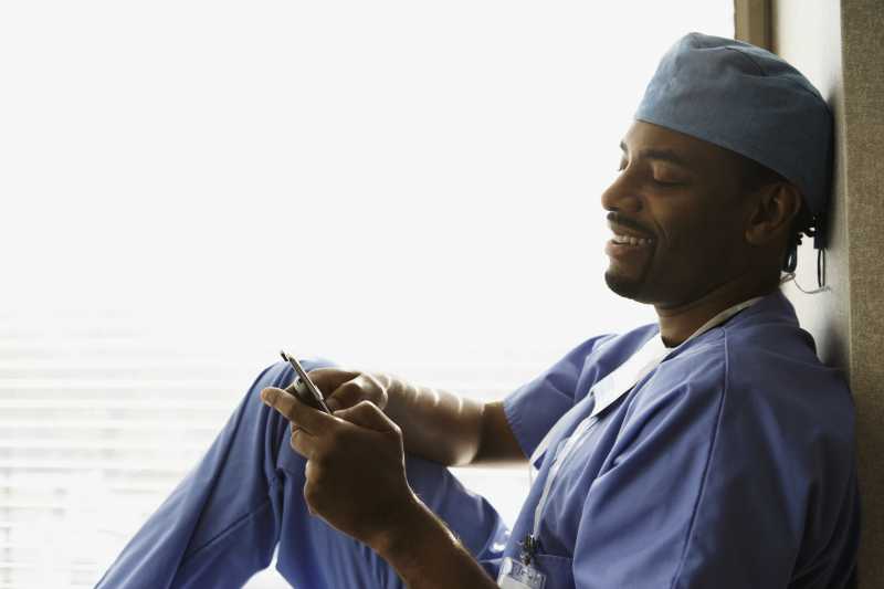 休息的男医生微笑的看着手机