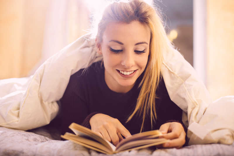 在床上趴着阅读的女孩