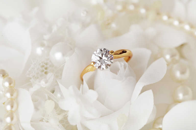 放在白色玫瑰花上的钻戒