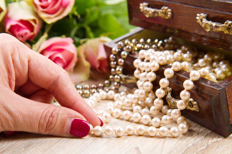 女人捏着露出首饰盒的珍珠项链