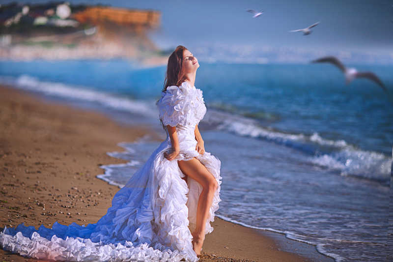 一个穿白色礼服的沙滩上的女孩